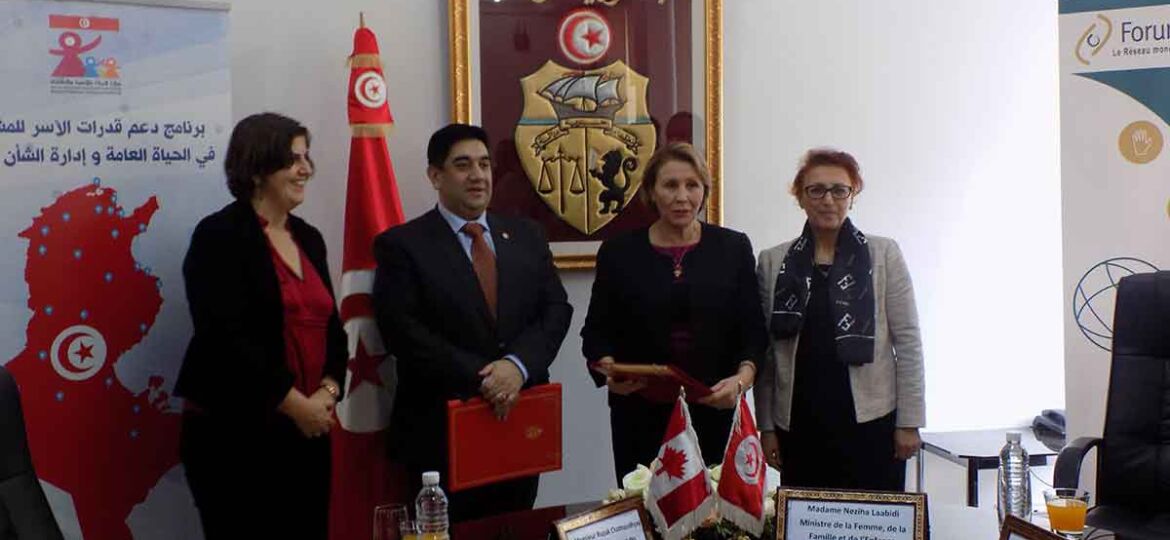 Four people posing for photo in front of Tunisia flag