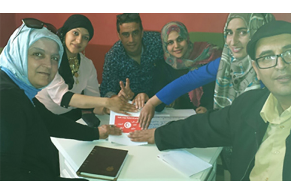 Group of people gathered around a table holding a paper with the Tunisian flag